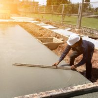 Man,hand,spreading,concrete,mix,with,trowel,in,foundation.,a