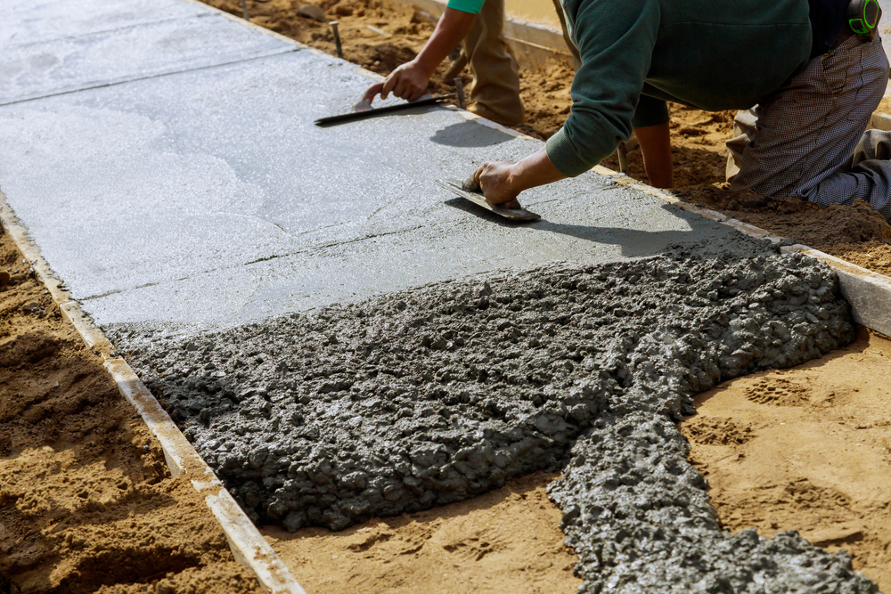 Laying,down,new,sidewalk,in,wet,concrete,on,freshly,poured